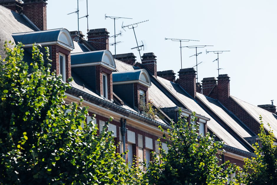 classes moyennes — Charmants toits et antennes à Amiens, mettant en valeur l'architecture française classique par une journée ensoleillée.