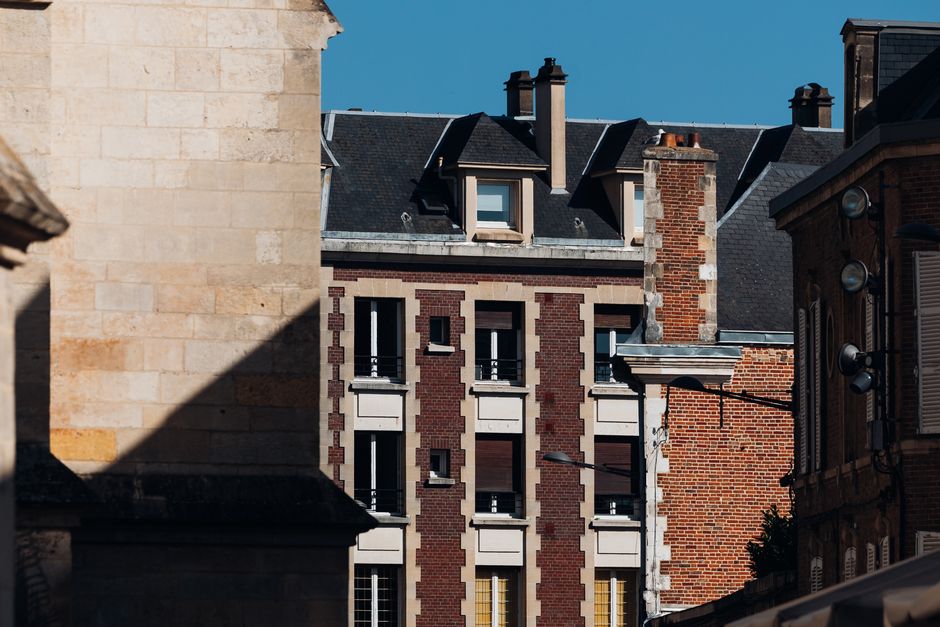 classes moyennes — Bâtiments historiques en briques et en pierre sous un ciel bleu clair à Amiens, France.