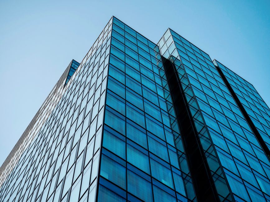immobilier d'entreprise — Vue en contre-plongée d'un gratte-ciel moderne avec une façade en verre réfléchissant atteignant