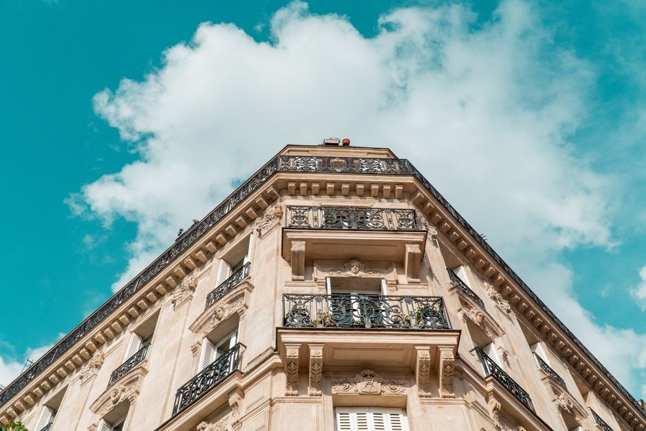 meilleurs taux immobiliers — Superbe façade d'immeuble parisien avec des balcons ornés sous un ciel vibrant.