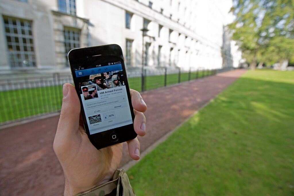 reseaux sociaux — A serviceman accesses social media channels using a smart phone, outside MOD Main Building in London MOD