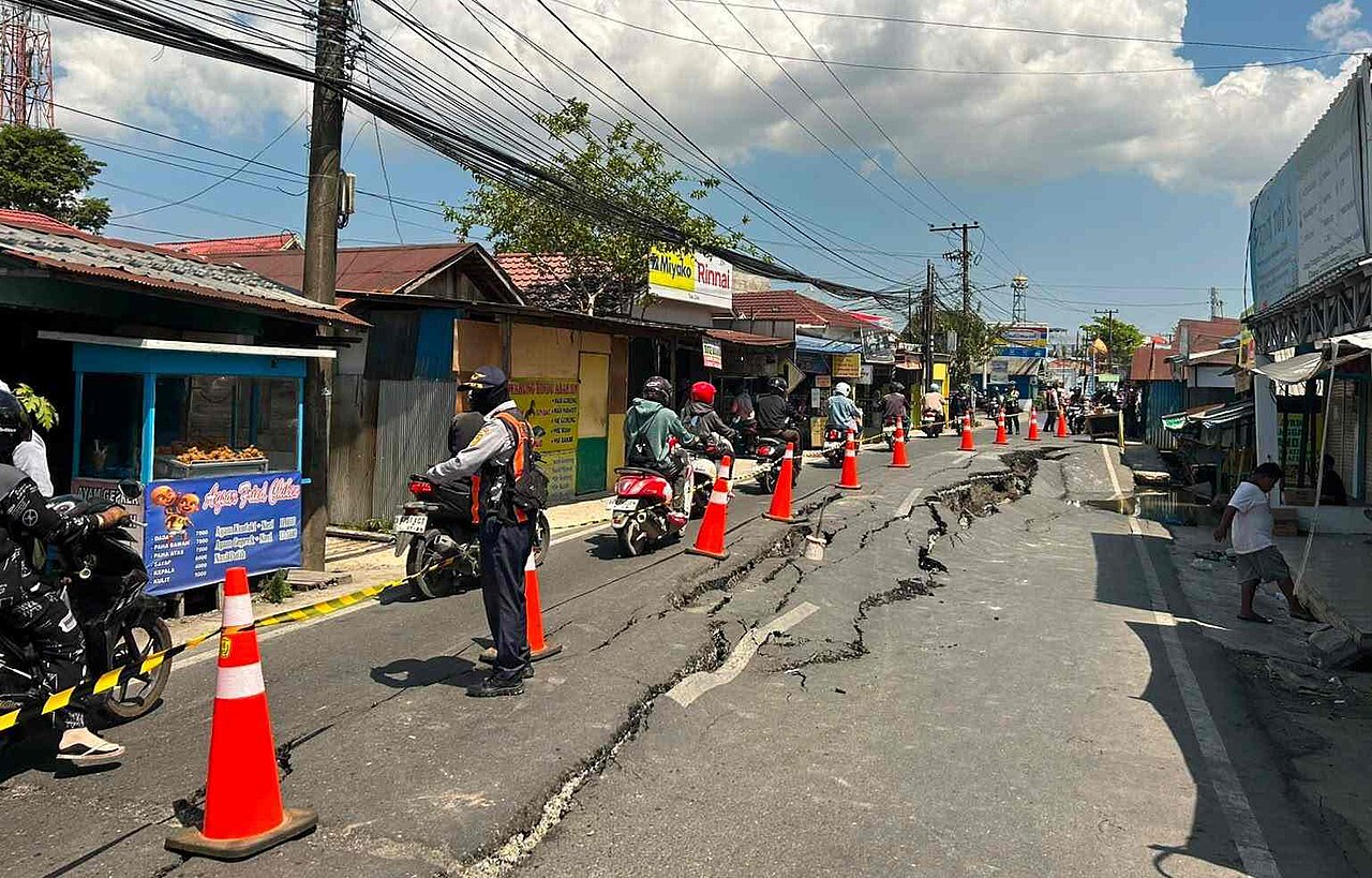 risques naturels et — Cracked Asphalt Road and Landslide Damage Caused by Natural Disaster with Traffic Officer Regulating Transportation
