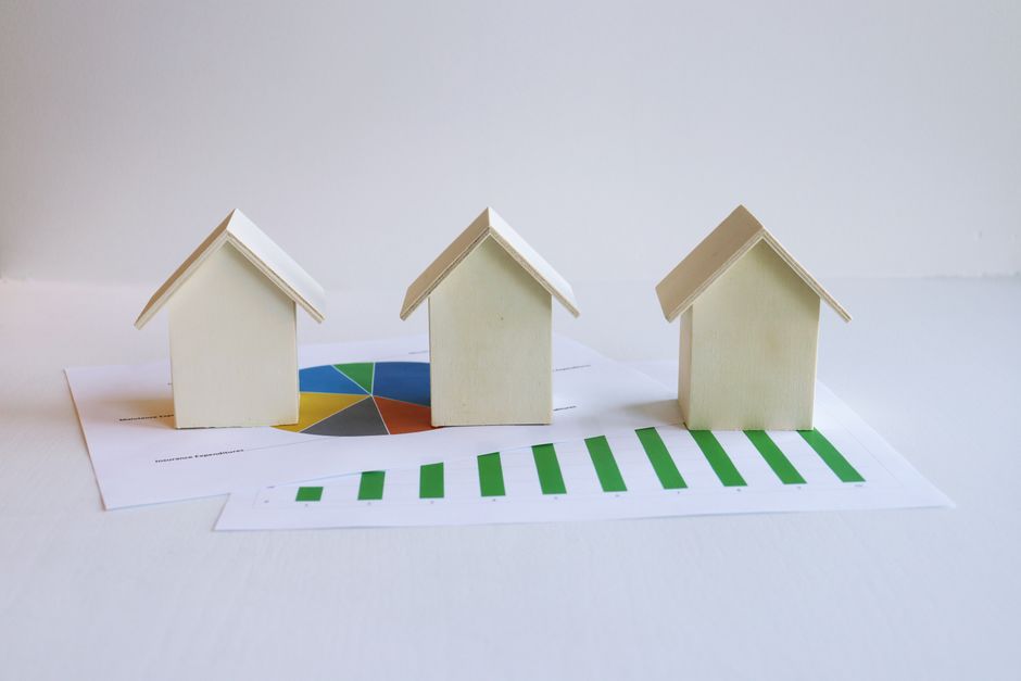 tendances du marche — Des maisons modèles en bois sur des graphiques représentant l'analyse et les tendances du marché immobilier.
