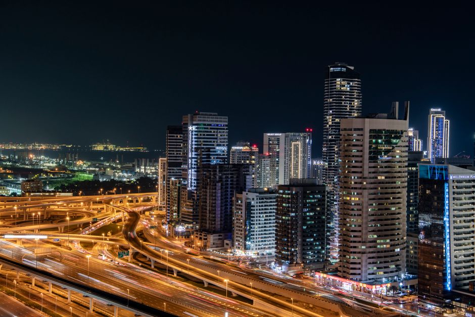 tendances du marche — Vue nocturne animée de l'horizon moderne de Dubaï avec des gratte-ciel illuminés et des autoroutes animées.